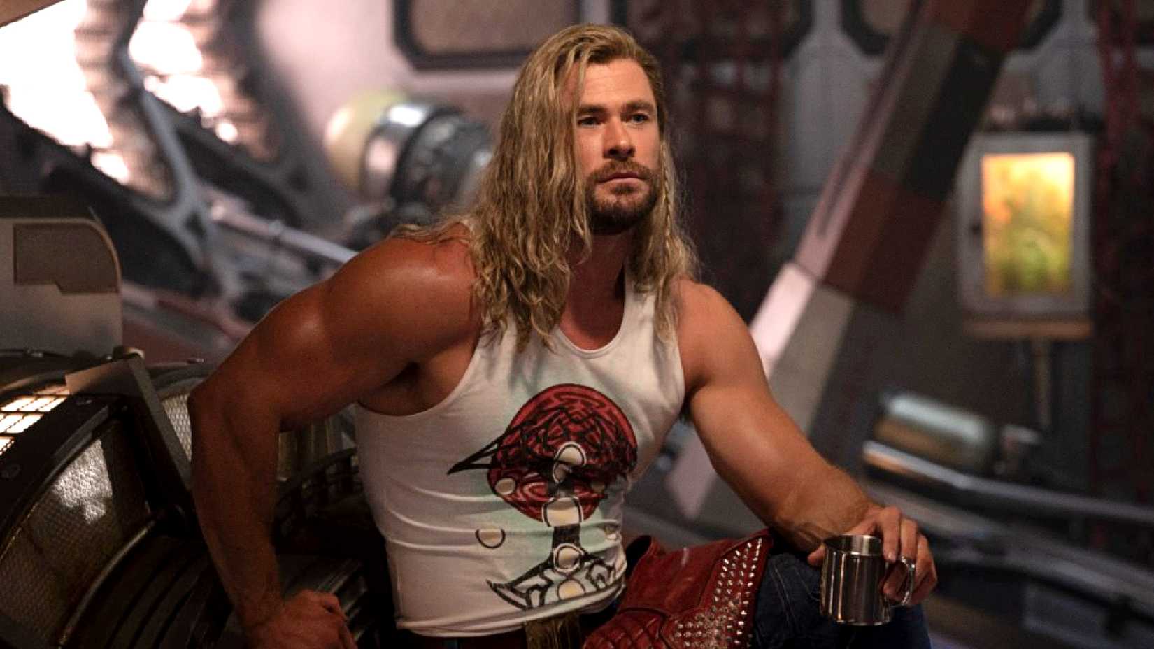 Chris Hemsworth's Thor holds a drink in his hand while showing off his muscles in Love and Thunder