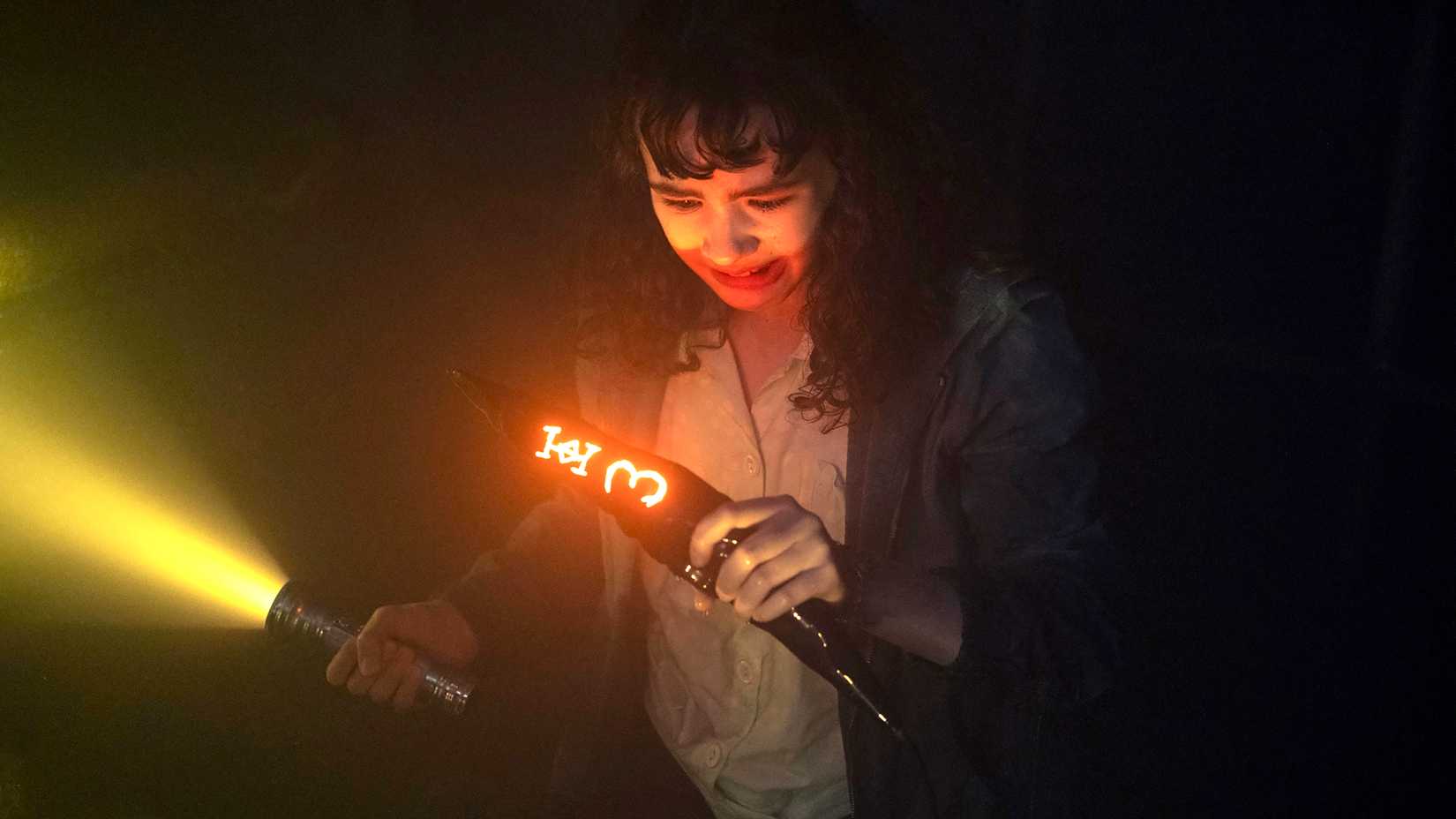 7 Pennywise Moments in IT: Welcome to Derry That Left Fans Stunned (Ranked) Clara Stack as Lilly looking scared while holding onto glowing shard and a flashlight in IT: Welcome to Derry episode 5