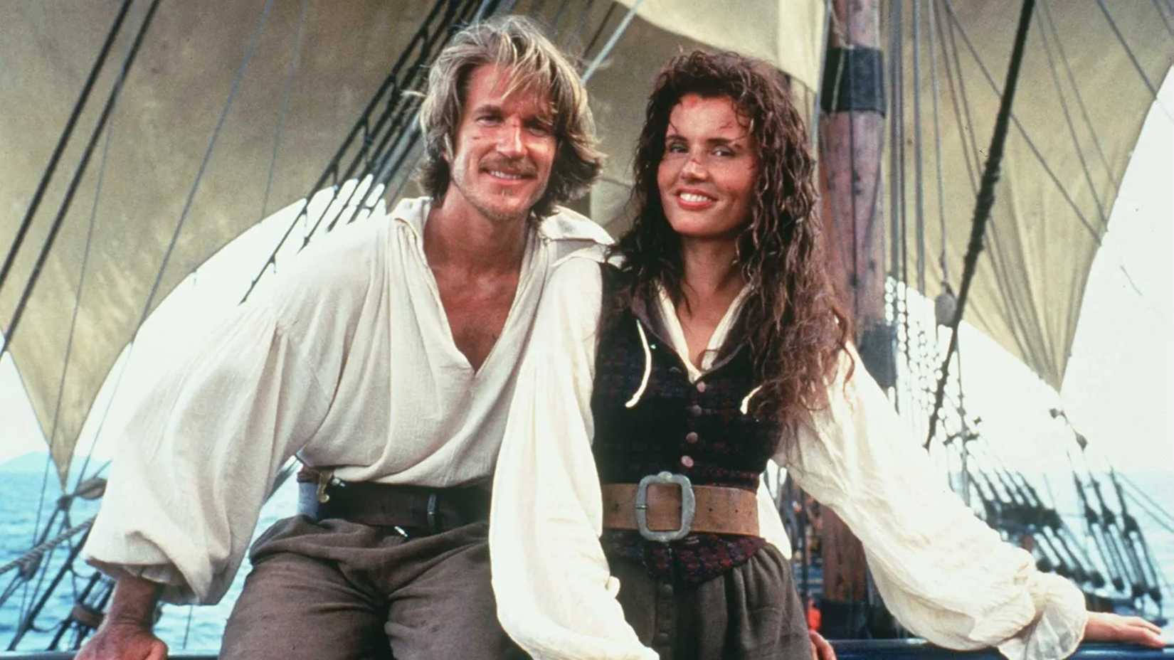 Matthew Modine and Gina Davis smile while standing on a boat in Cutthroat Island