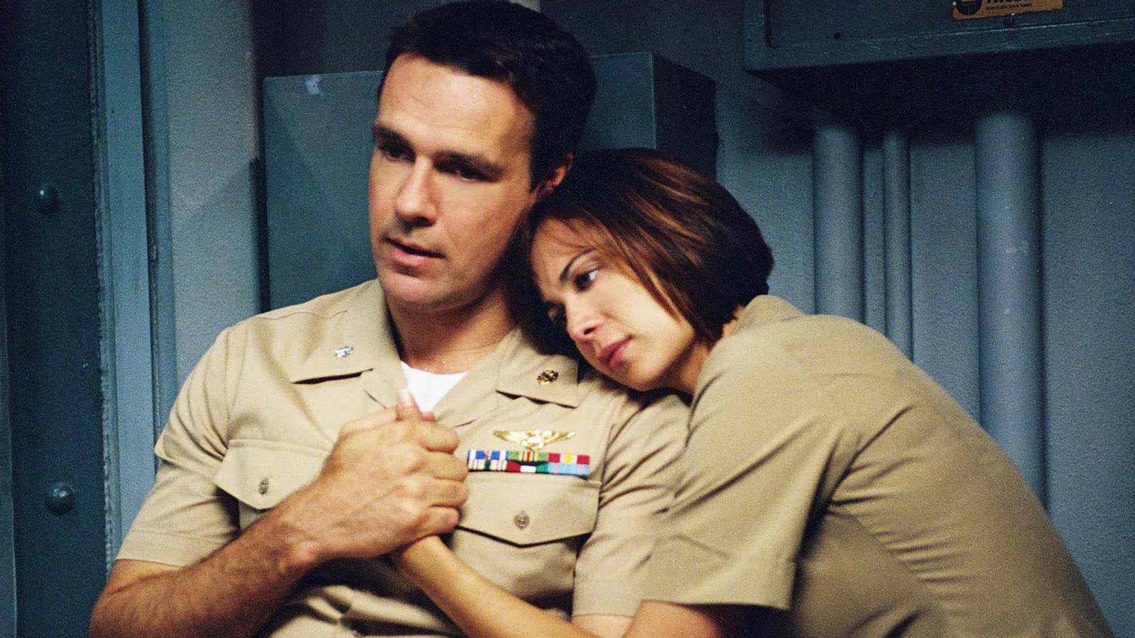 David James Elliott's Harm and Catherine Bell's Mac looking emotional and laying next to each other in JAG