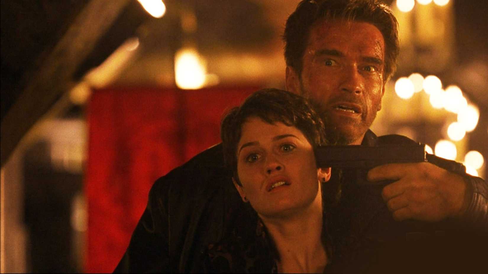 Arnold Schwarzenegger points a gun at a woman's head in End of Days