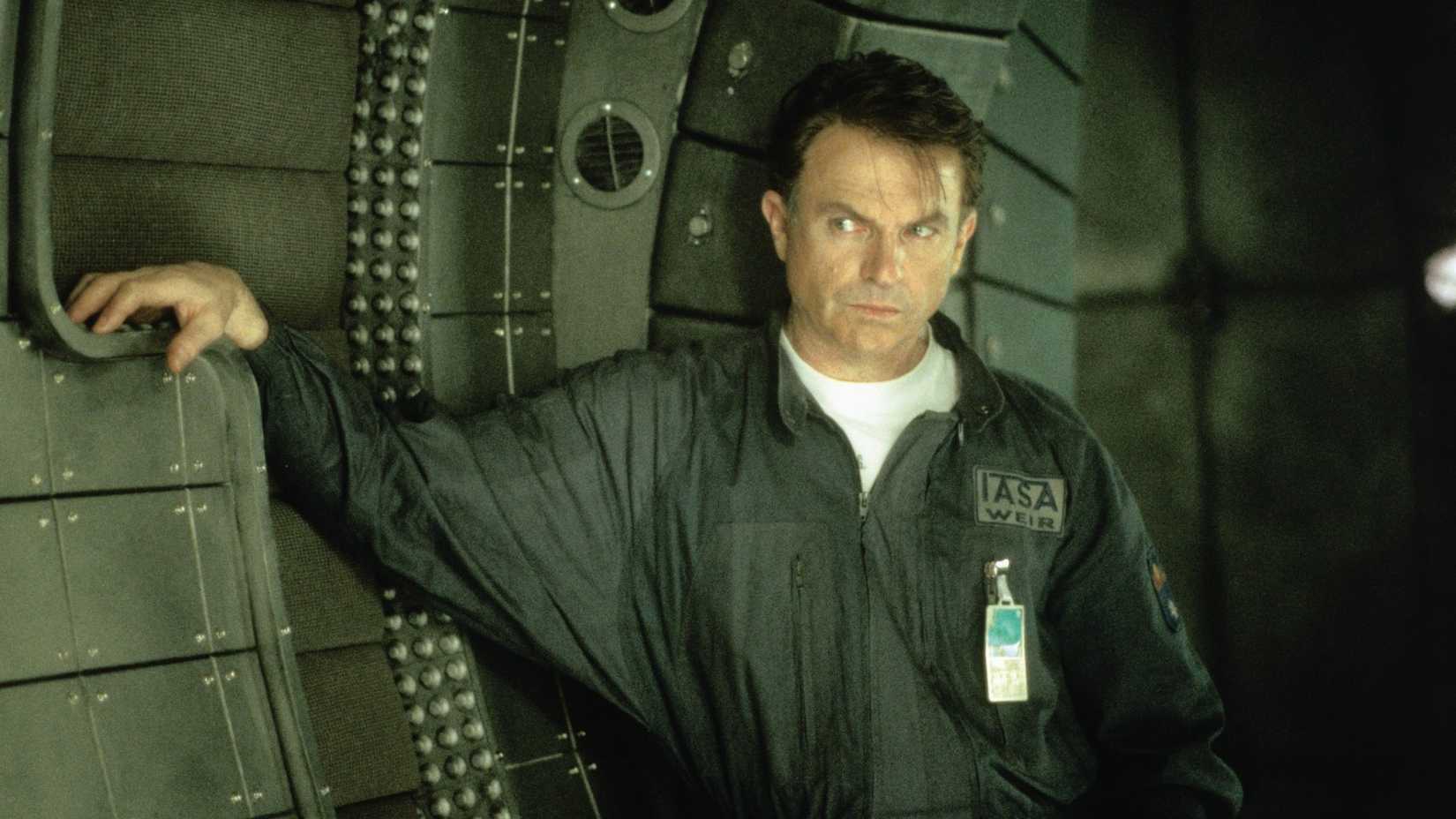 Sam Neill leans against a wall in Event Horizon