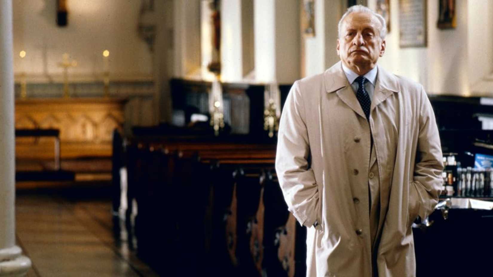 Kinderman está com as mãos nos bolsos em uma igreja em Exorcist III