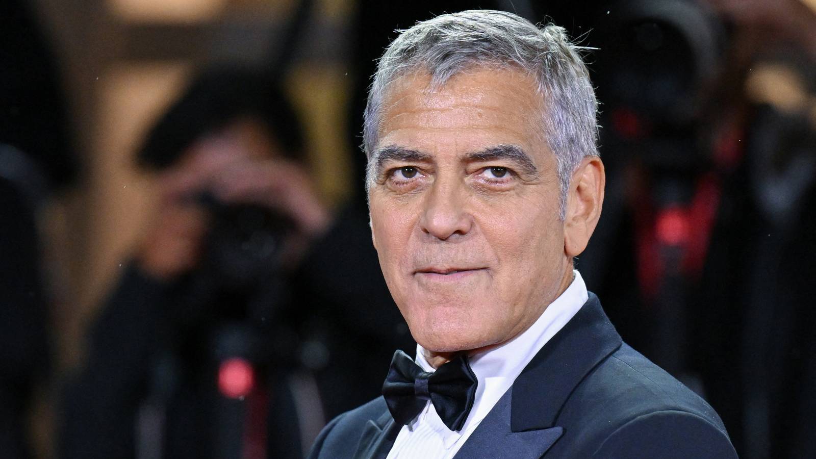 George Clooney looks to the left with a neutral expression while attending an event