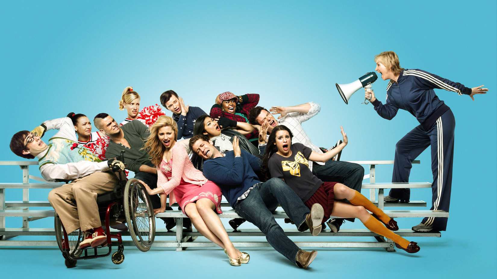 Elenco de Glee se inclinando para a esquerda enquanto Sue Sylvester grita com eles com um megafone.