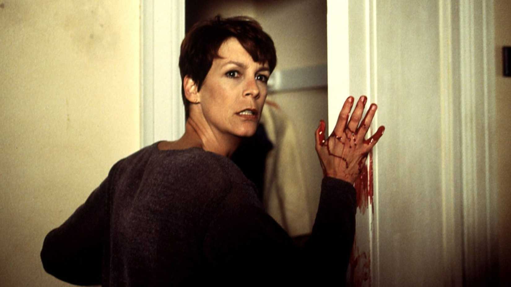 Every Version & Canon Status 2 Laurie puts a bloody hand on a doorframe in Halloween H20
