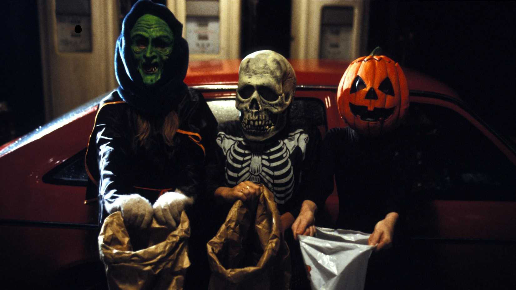 Three kids in halloween masks stand by a car in Halloween III Season of the Witch