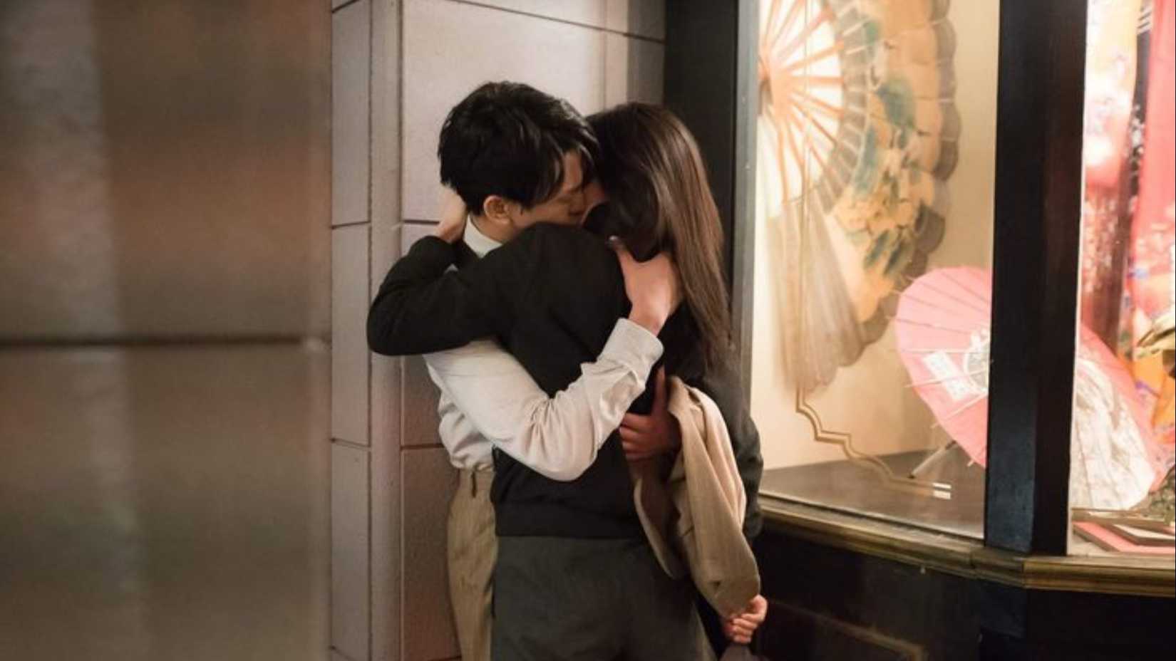 A man and woman kiss behind a wall in Chicago Typewriter.