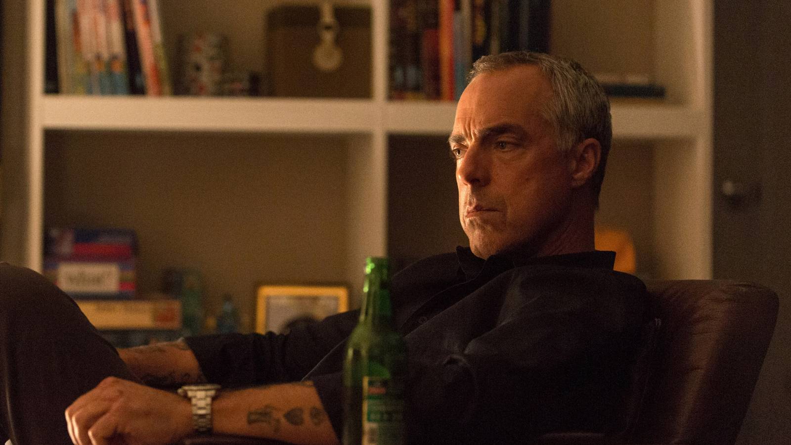Harry Bosch sits in a chair with a contemplative look on his face in Bosch