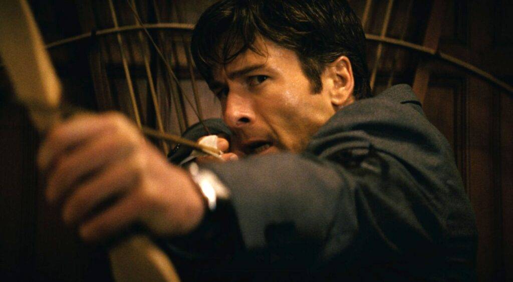 Glen Powell aiming a bow and arrow in How to Make a Killing