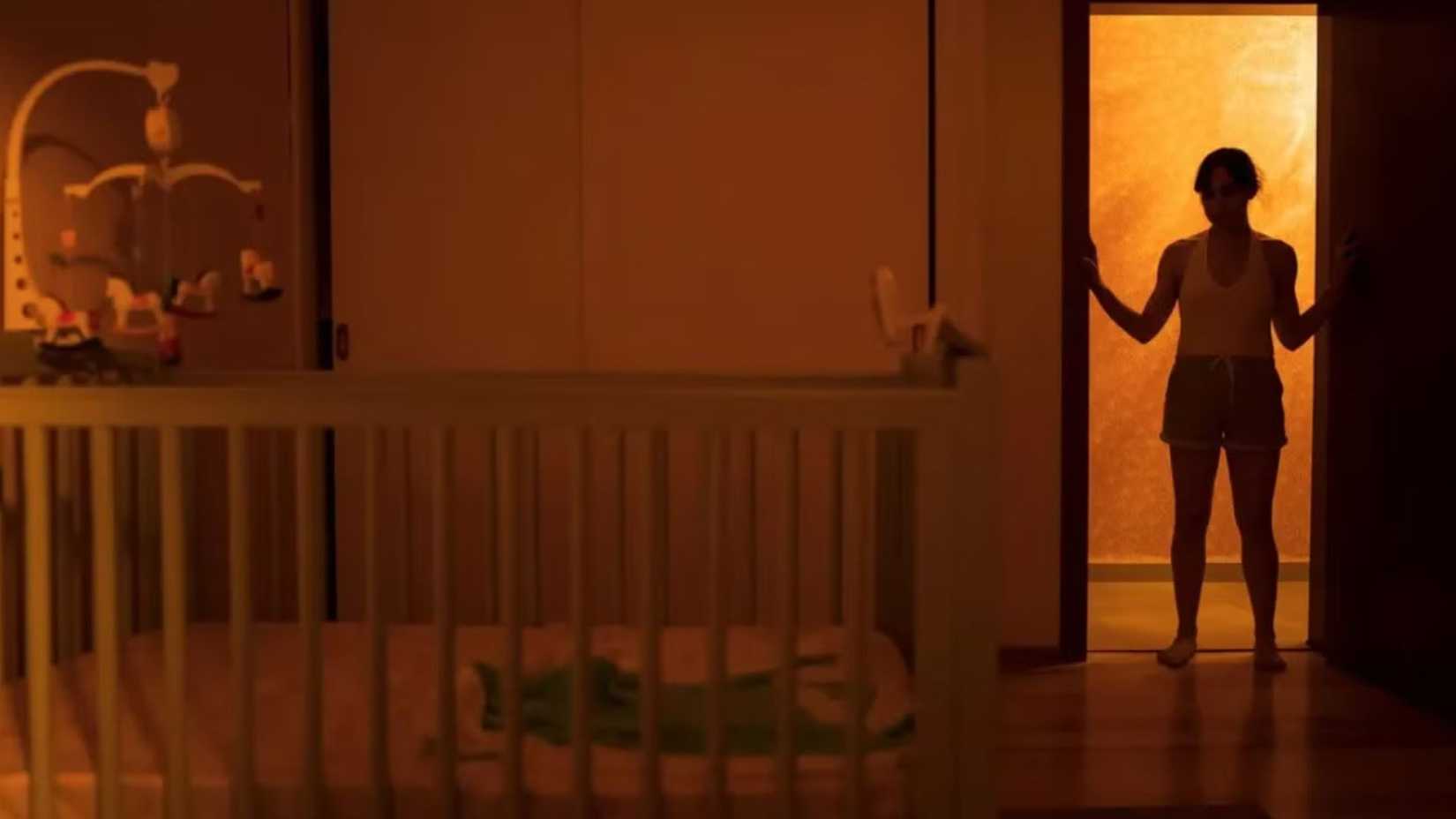 Huesera The Bone Woman character stands in a doorway looking at the crib