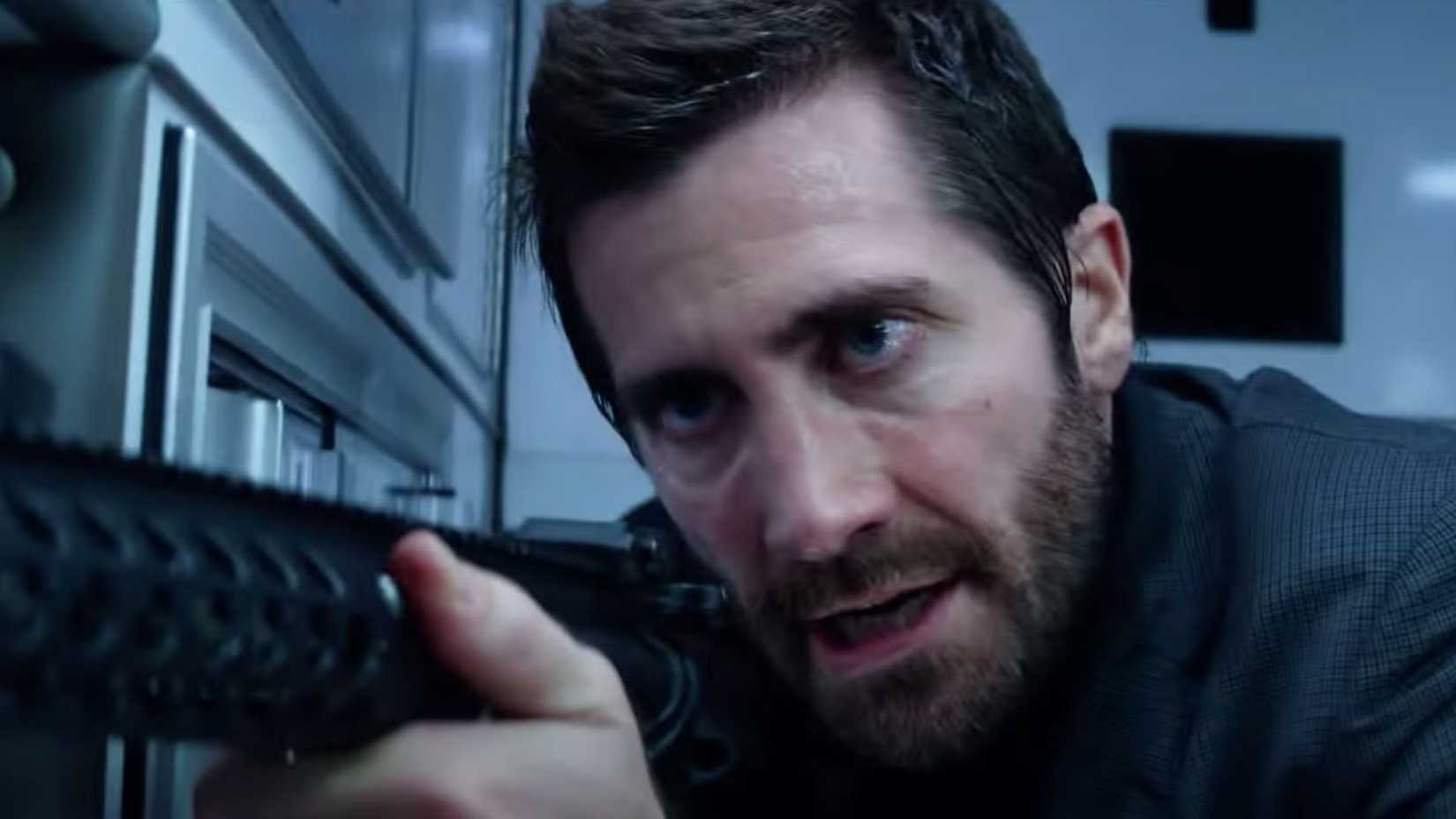 Jake Gyllenhaal com uma metralhadora em Ambulance.
