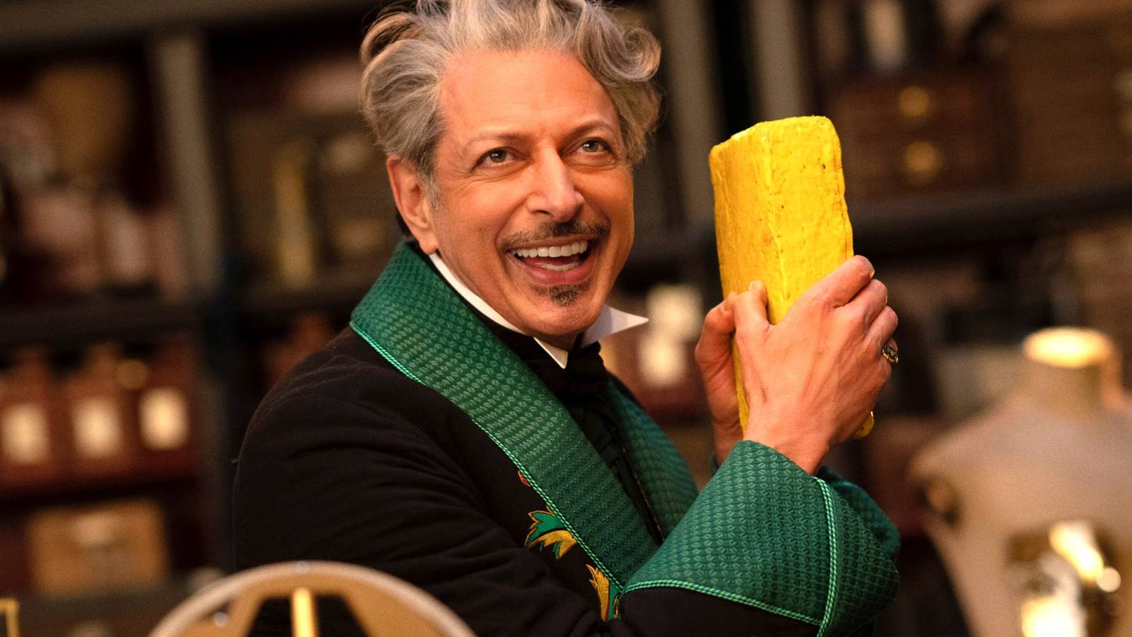 Jeff Goldblum as The Wizard smiling and holding a yellow brick in Wicked For Good