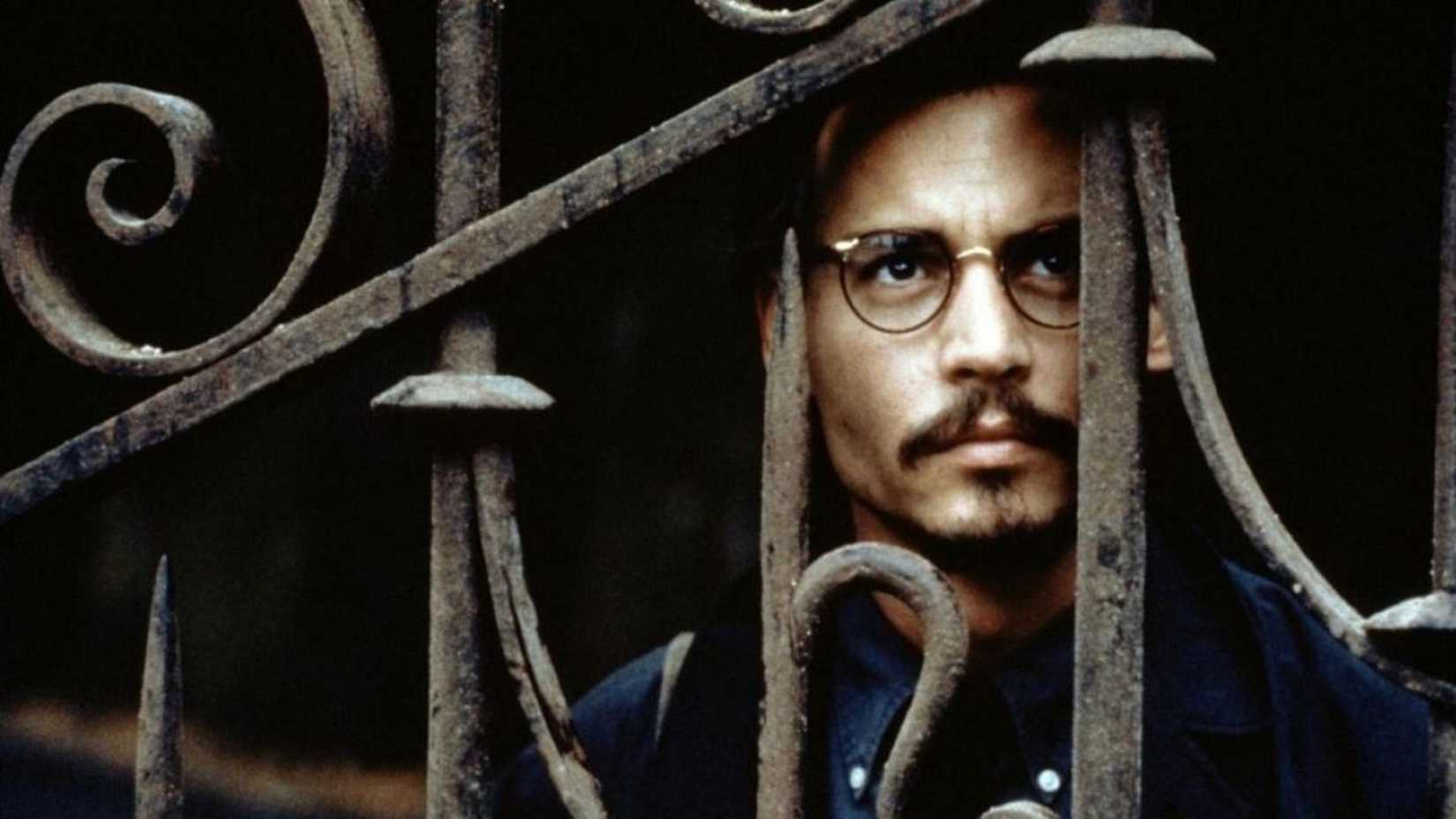 Johnny Depp as Dean Corso looking through a gate in The Ninth Gate