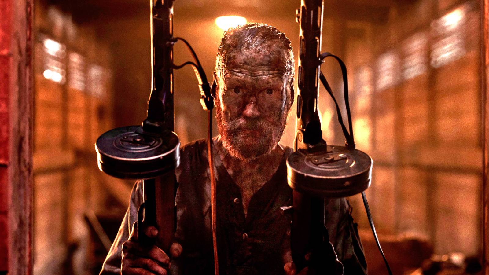 Jorma Tommila's Aatami holding two Tommy guns while covered in mud and looking intense in Sisu: Road to Revenge