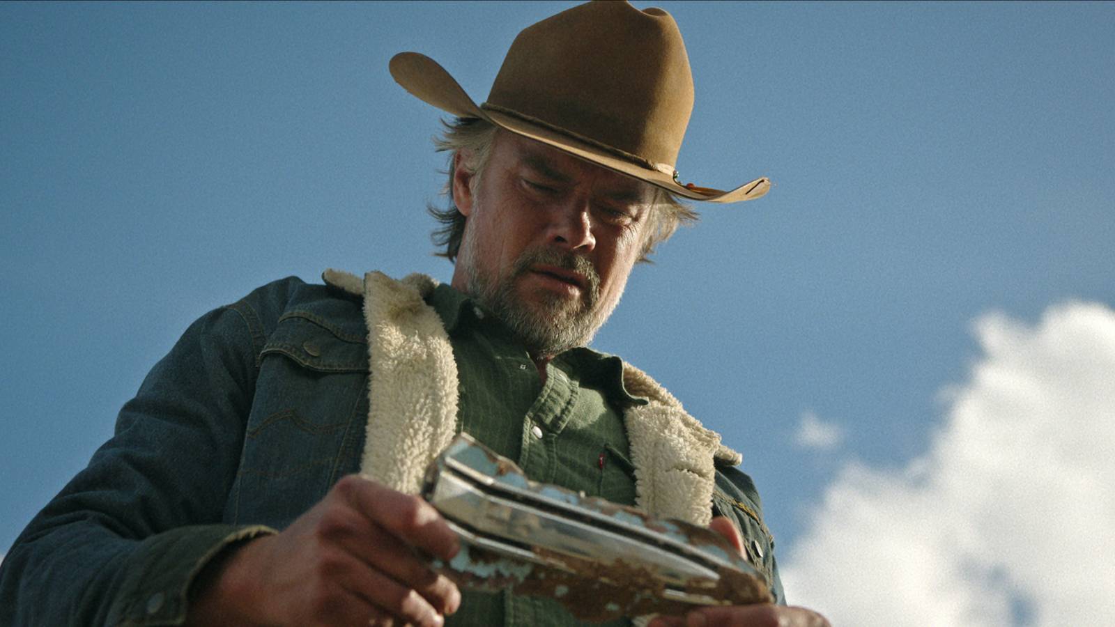 Josh Duhamel looking down at something in his hand in Ransom Canyon