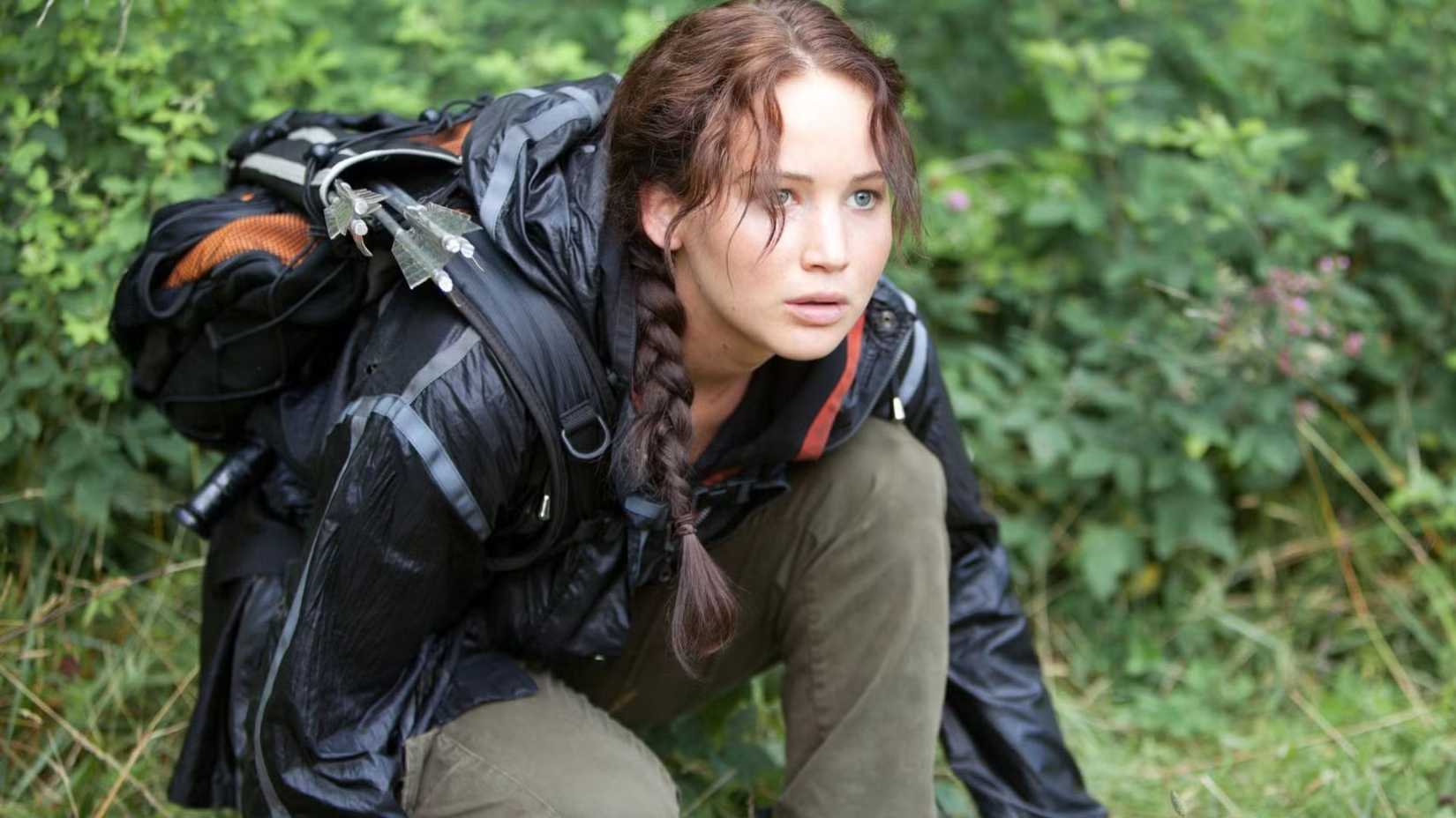 Katniss ajoelhada e chocada em The Hunger Games