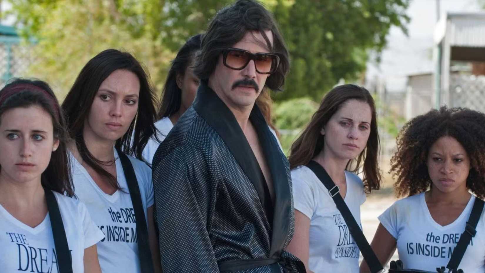 Keanu Reeves as The Dream is surrounded by armed women in The Bad Batch