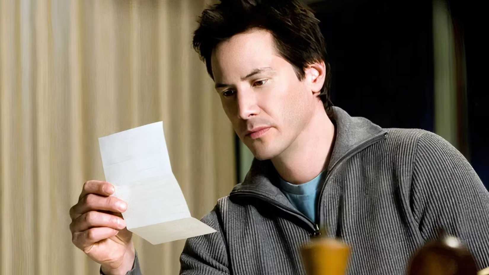 Keanu Reeves looking at a letter in The Lake House