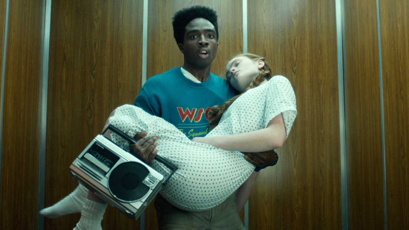 Lucas carrega Max inconsciente em um elevador na quinta temporada de Stranger Things