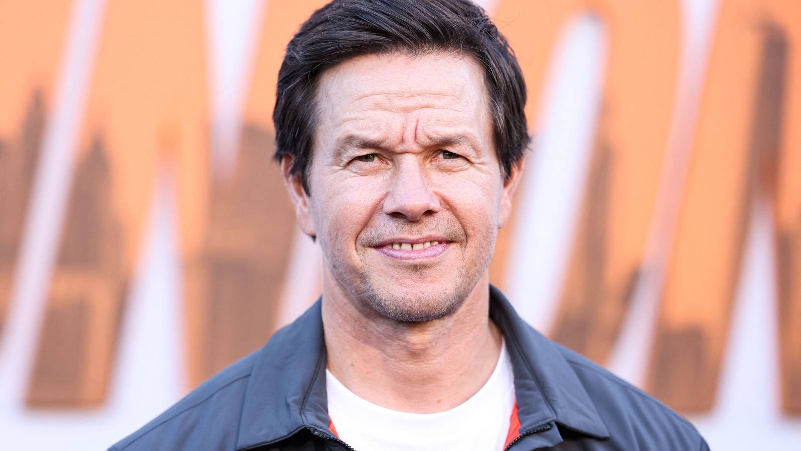 Mark Wahlberg smiles while looking slightly to the right during a red carpet event