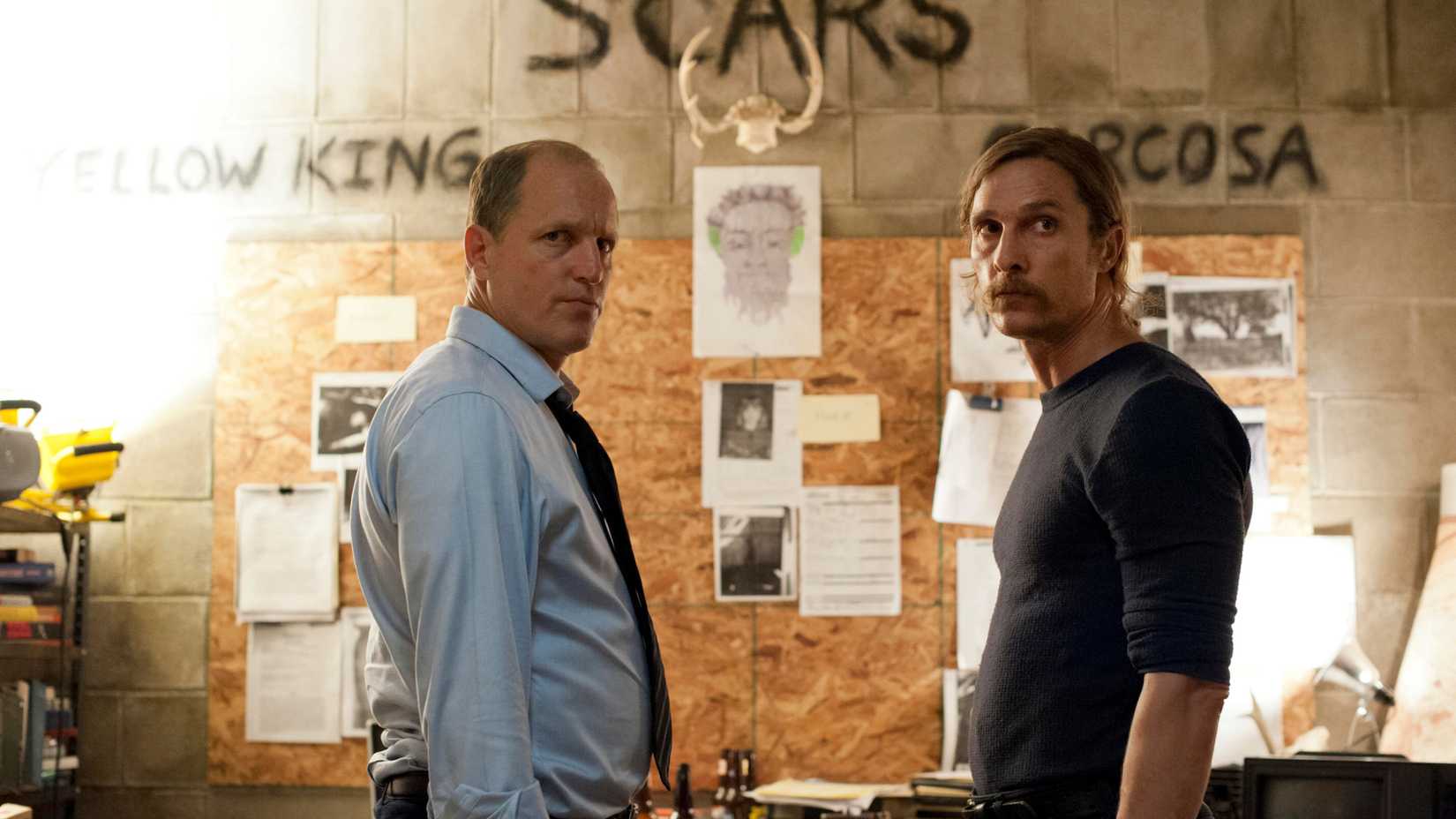 martin hart and rust cohle standing parallel each other in front of a detective investigation board in true detective