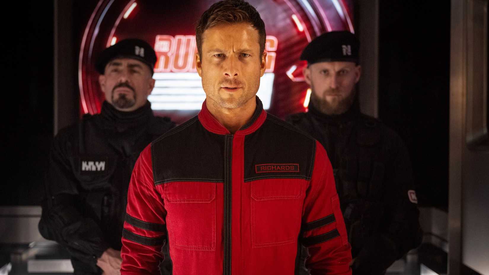 Ben Richards (Glen Powell) flanked looking serious in The Running Man
