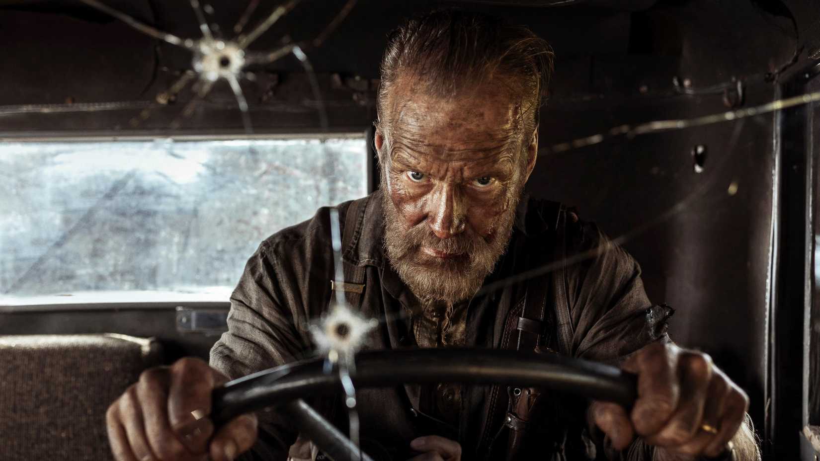 Jorma Tommila as Aatami Korpi driving a vehicle with a bullet-riddled window in Sisu: Road to Revenge