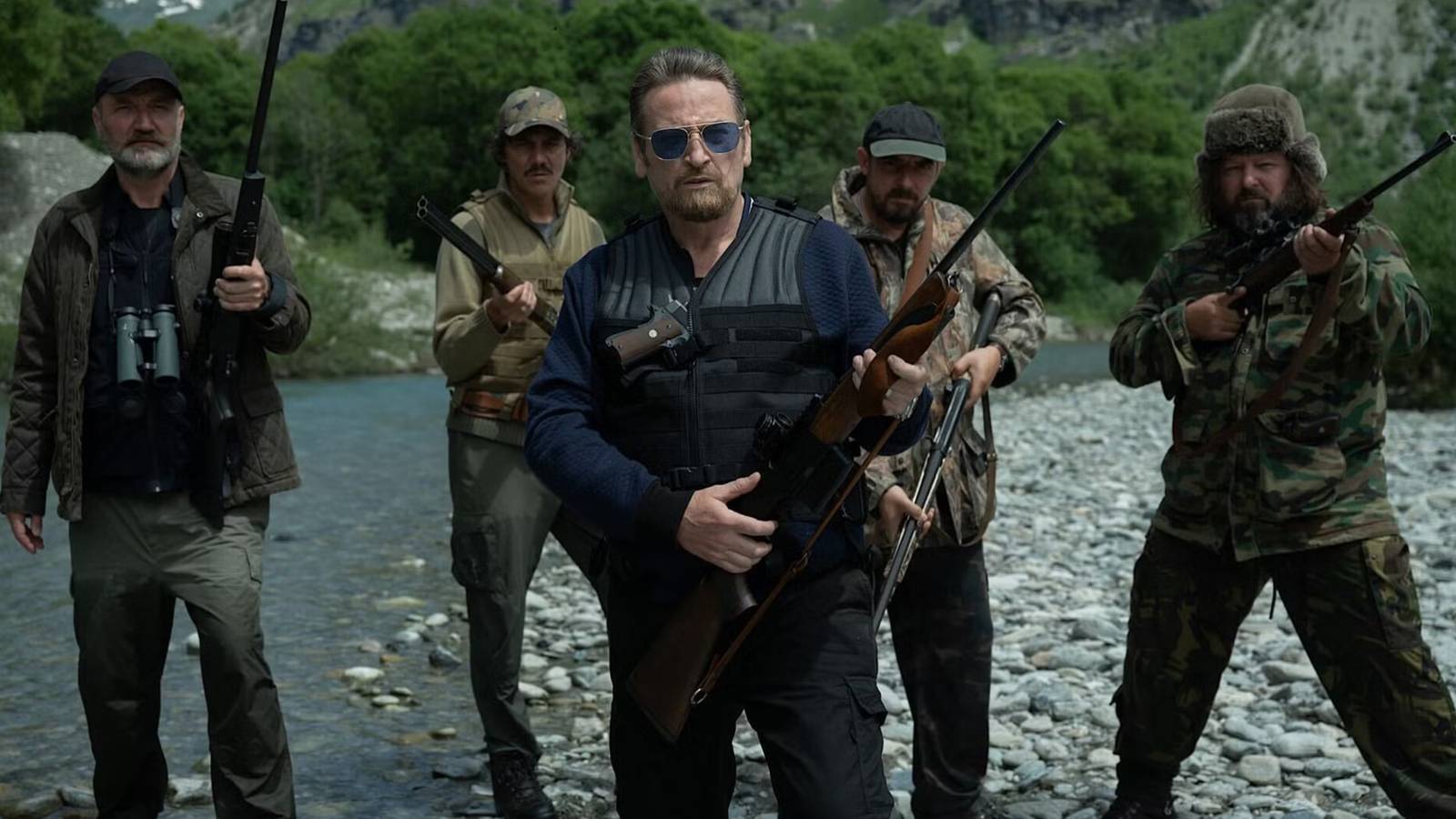 Men with guns stand in the water in The Hunt