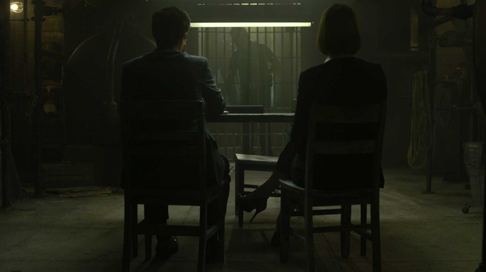 Anna Torv and Joe Tuttle sitting with their backs to the camera in a prison in Mindhunter