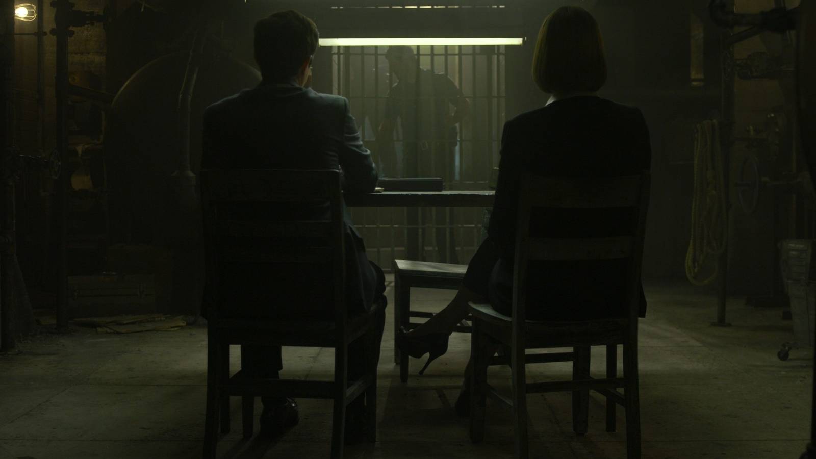 Anna Torv and Joe Tuttle sitting with their backs to the camera in a prison in Mindhunter