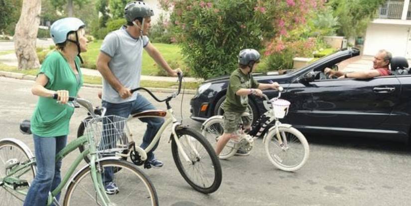Claire, Phil, and Luke riding bikes talking to Jay driving on Modern Family