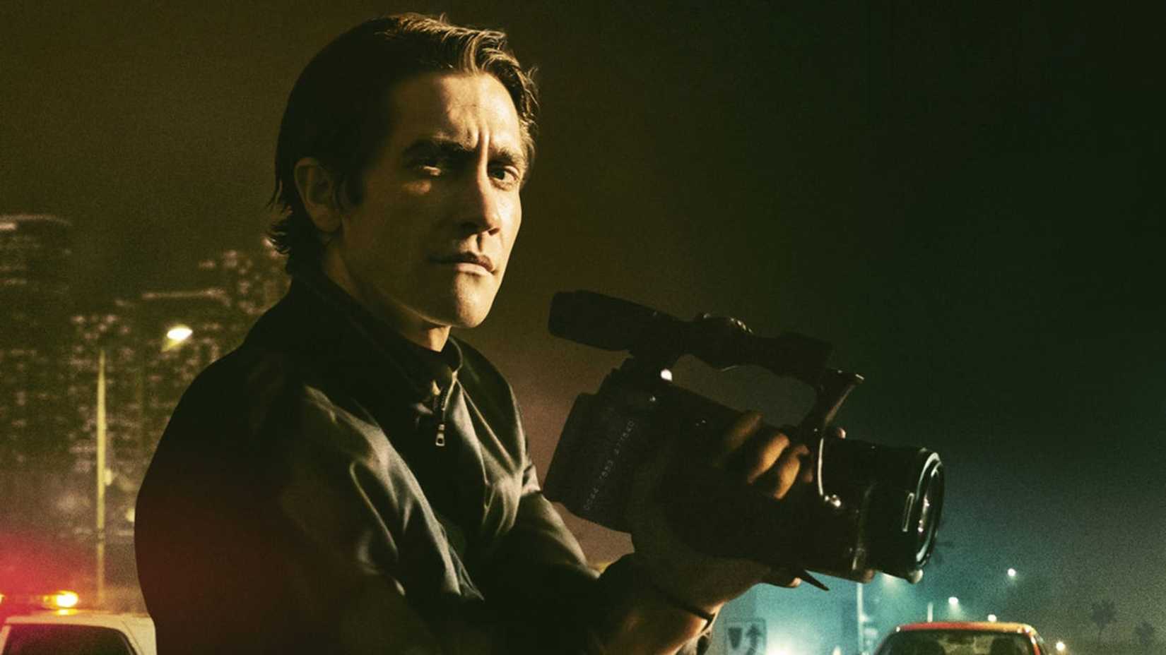 Jake Gyllenhaal segura uma câmera contra o pano de fundo da cidade em Nightcrawler.