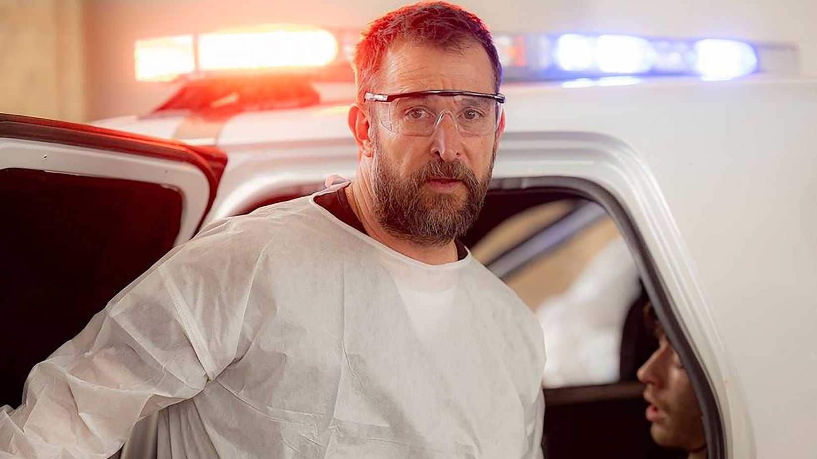 Noah Wyles Dr. Robby wirkt besorgt, während er in einem weißen medizinischen Anzug neben einem Auto in The Pitt ist