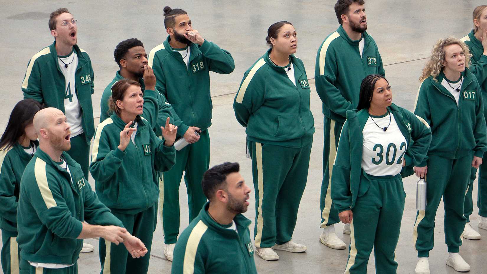 Vários participantes parecendo chateados e chocados olhando para uma tela em Squid Game: The Challenge temporada 2
