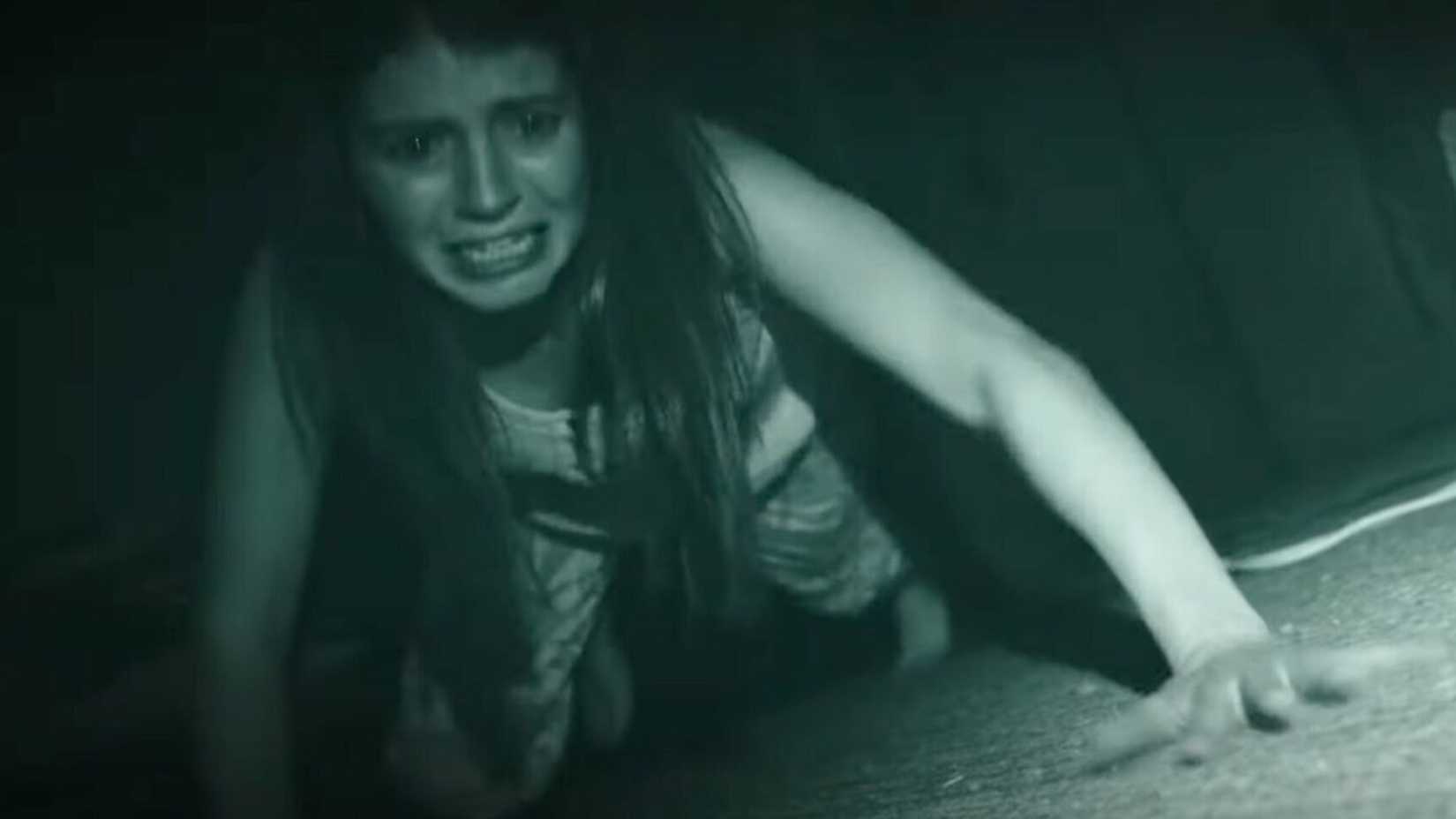 Uma mulher engatinha no chão parecendo assustada em Paranormal Activity Next of Kin