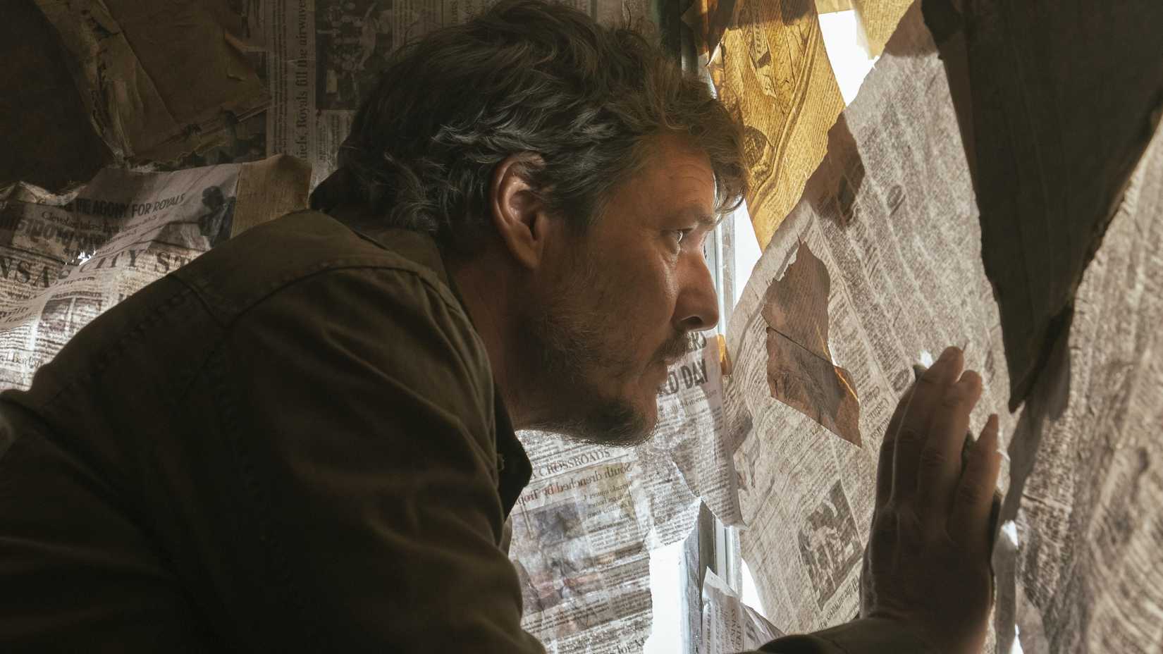 Pedro Pascal como Joel olhando pela janela na primeira temporada de The Last of Us
