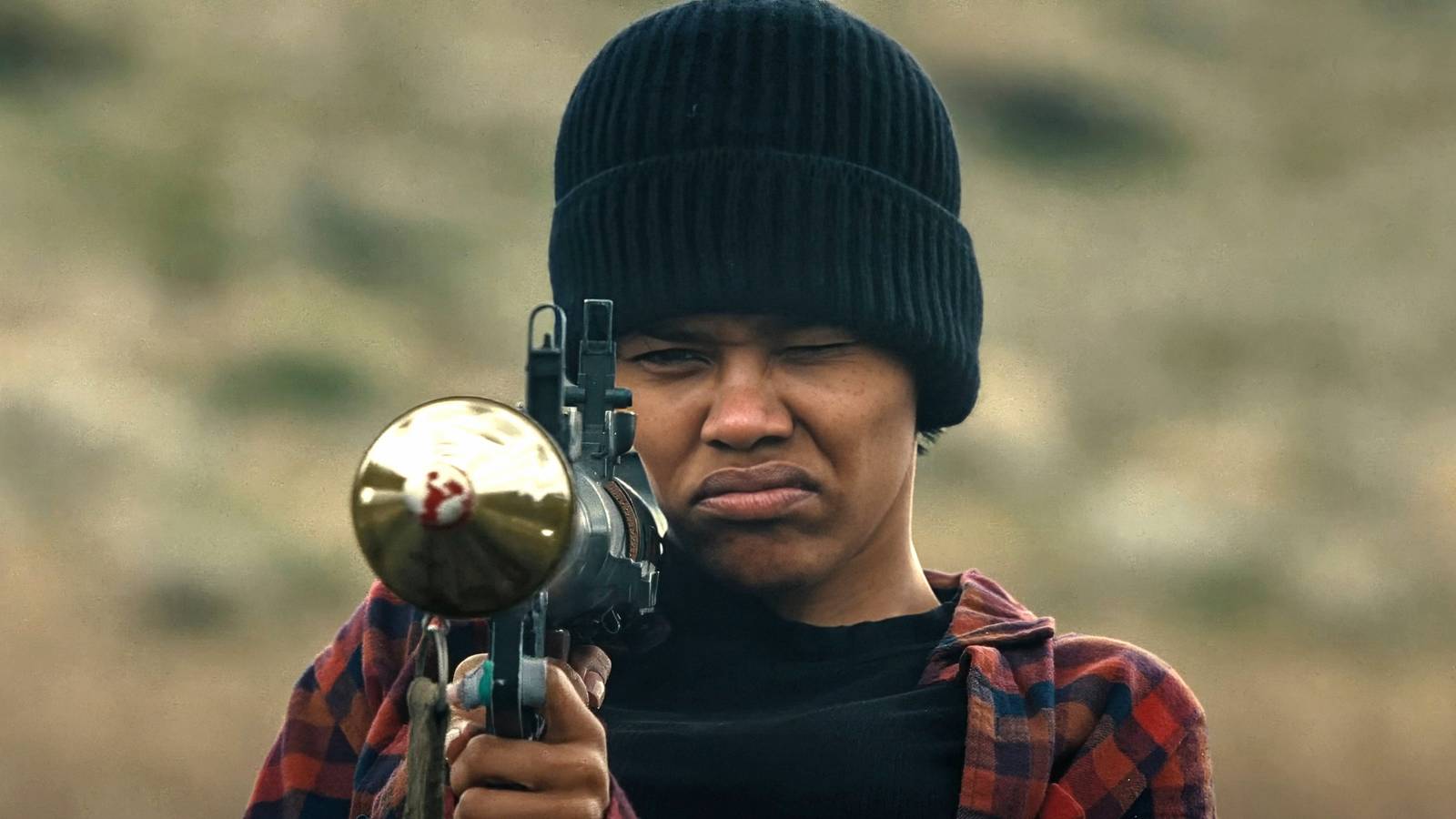 Perfidia Beverly Hills aiming a rocket launcher in close-up in One Battle After Another