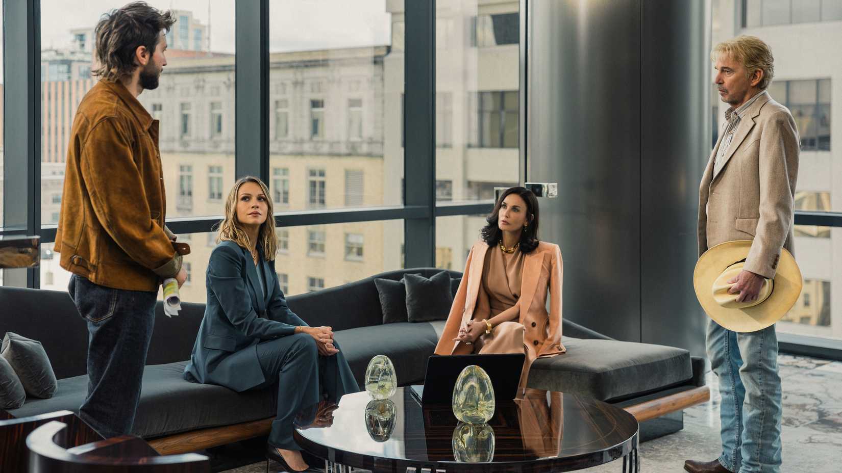 Rebecca and Cami looking at Tommy and someone else while in a living room in Landman season 2