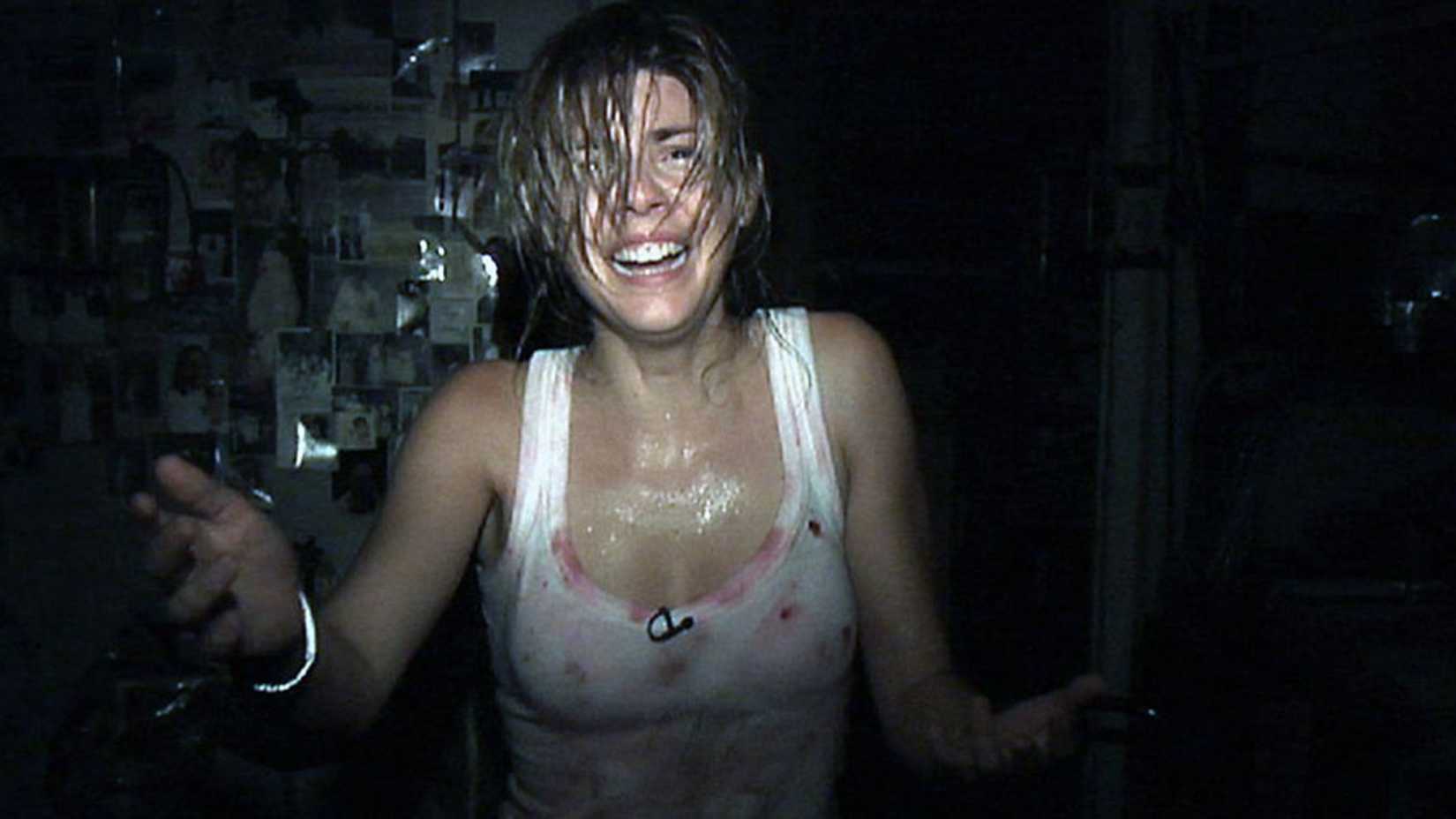 Uma mulher chora enquanto estende a mão para a câmera em [REC] 2007