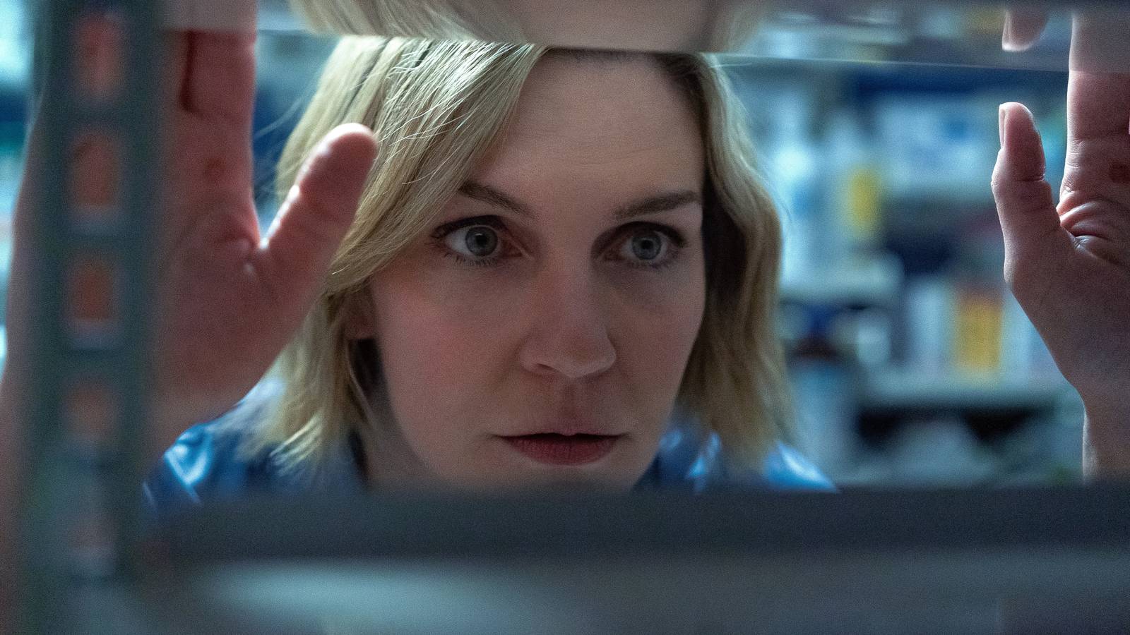 Rhea Seehorn as Carol looking intently at a shelf in Pluribus