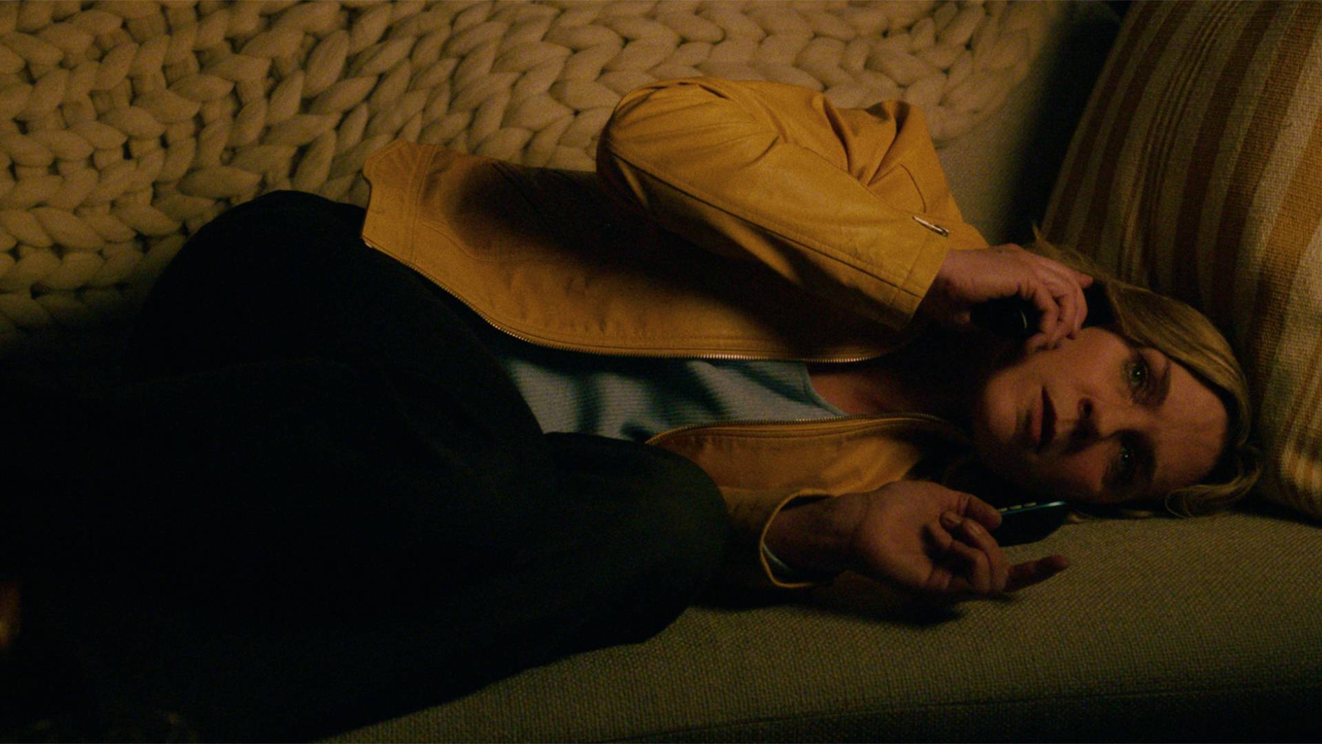 Rhea Seehorn curled up on the couch in Pluribus