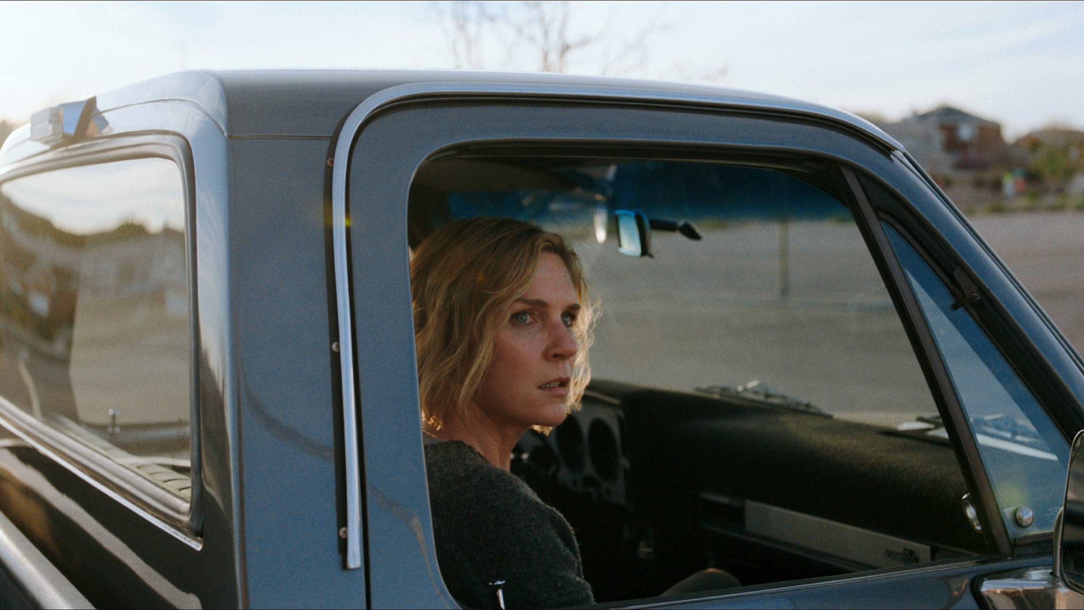 Rhea Seehorn gazes out through a pick-up truck window in a scene from Pluribus.