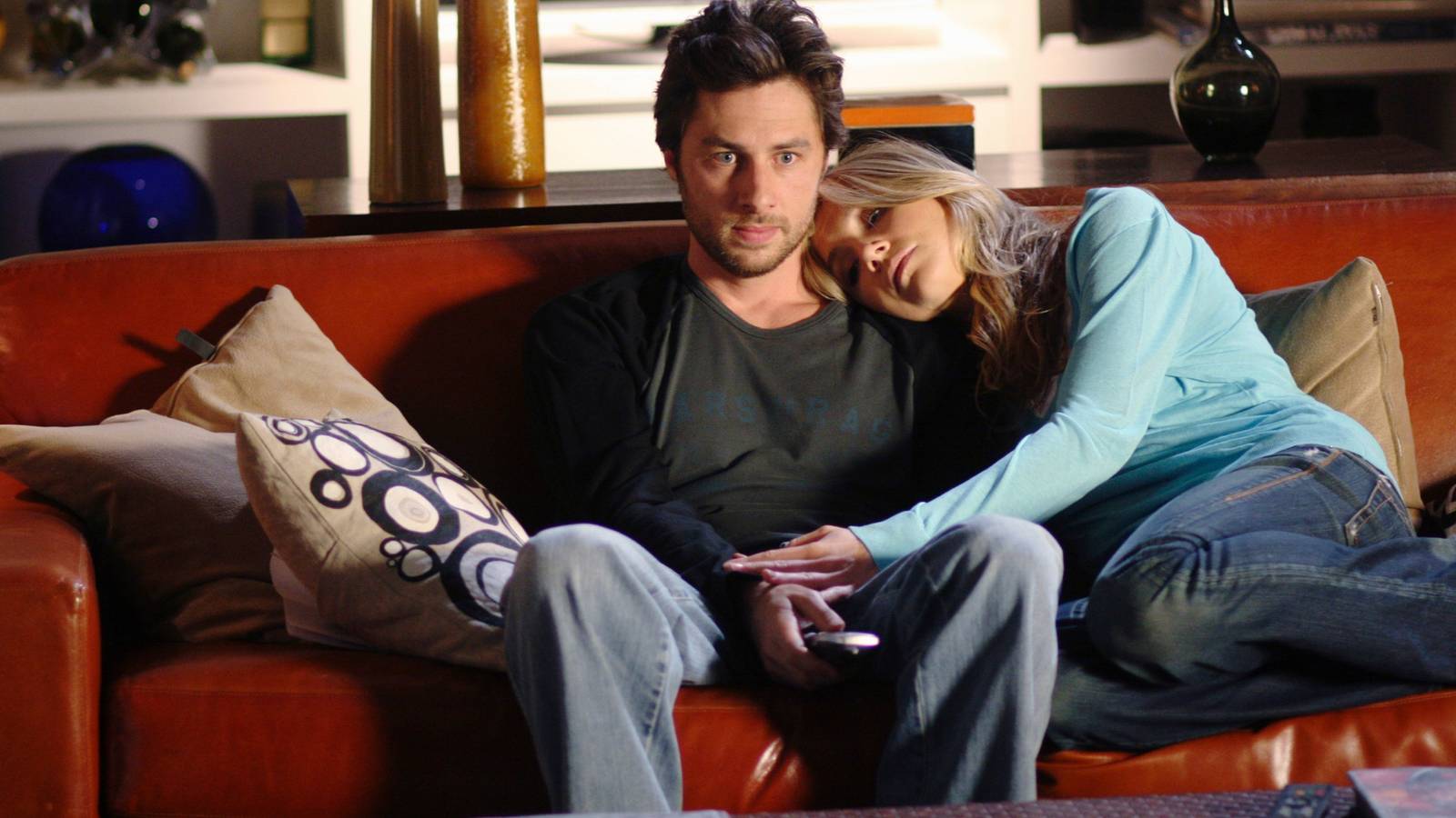 Zach Braff and Sarah Chalke cuddling on a couch in Scrubs
