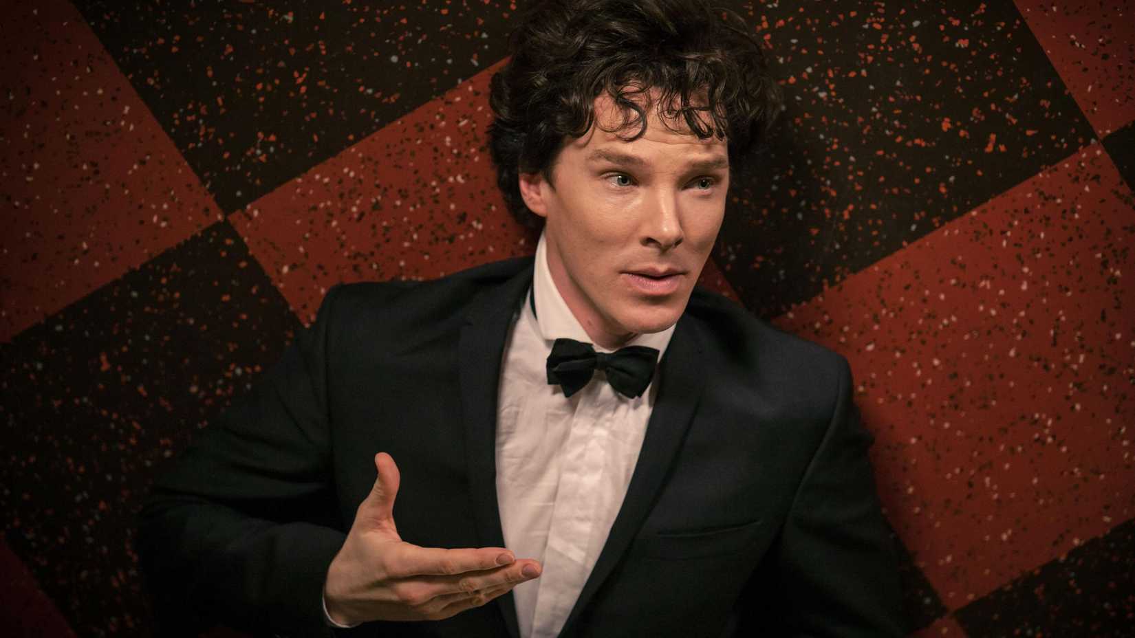 Sherlock Holmes (Benedict Cumberbatch) raising his hand and smiling in Sherlock.