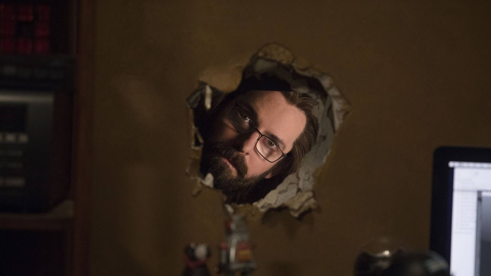 Gilfoyle (Martin Starr) looking through a hole in the wall in Silicon Valley.