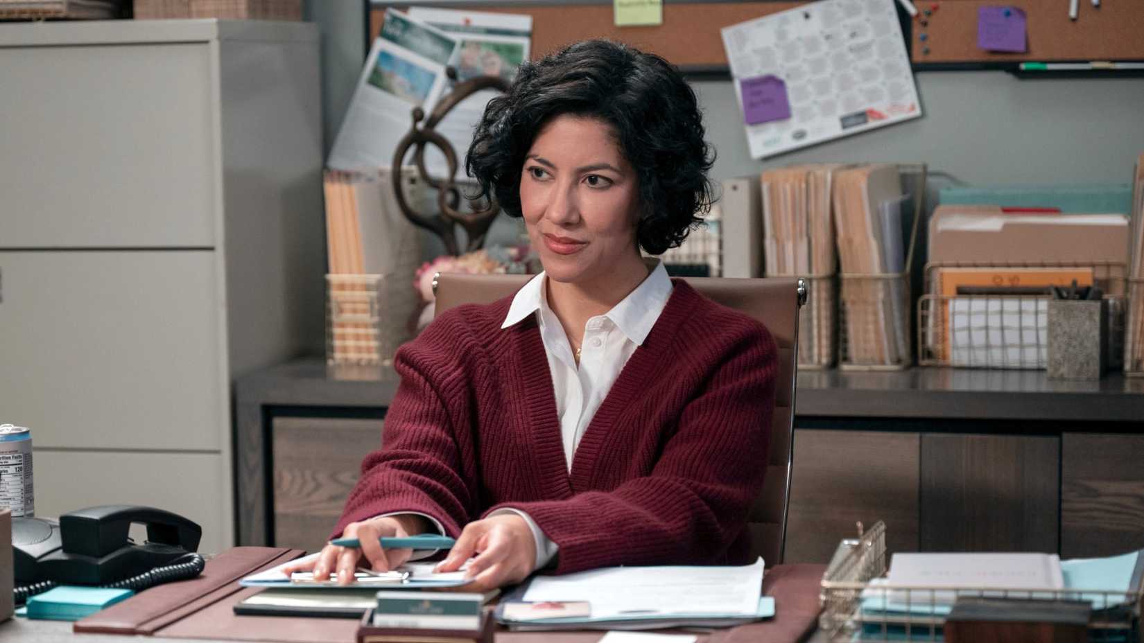 stephanie beatriz sitting at a desk in a man on the inside