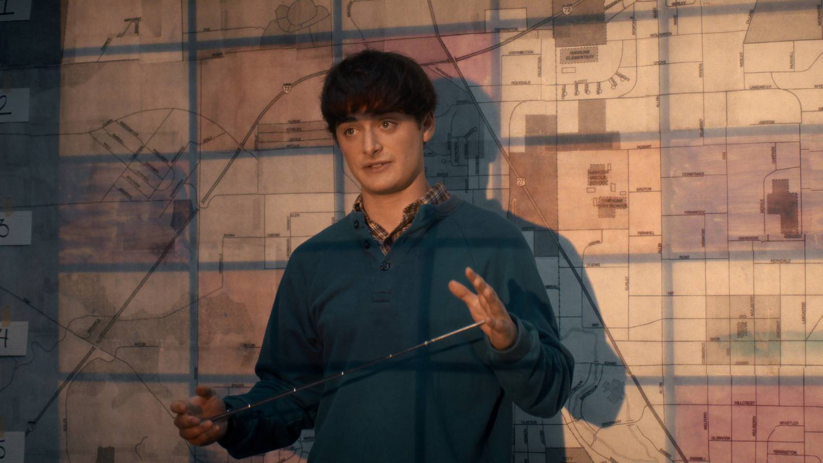 Stranger Things still featuring Will Byer standing in front of a projected map.