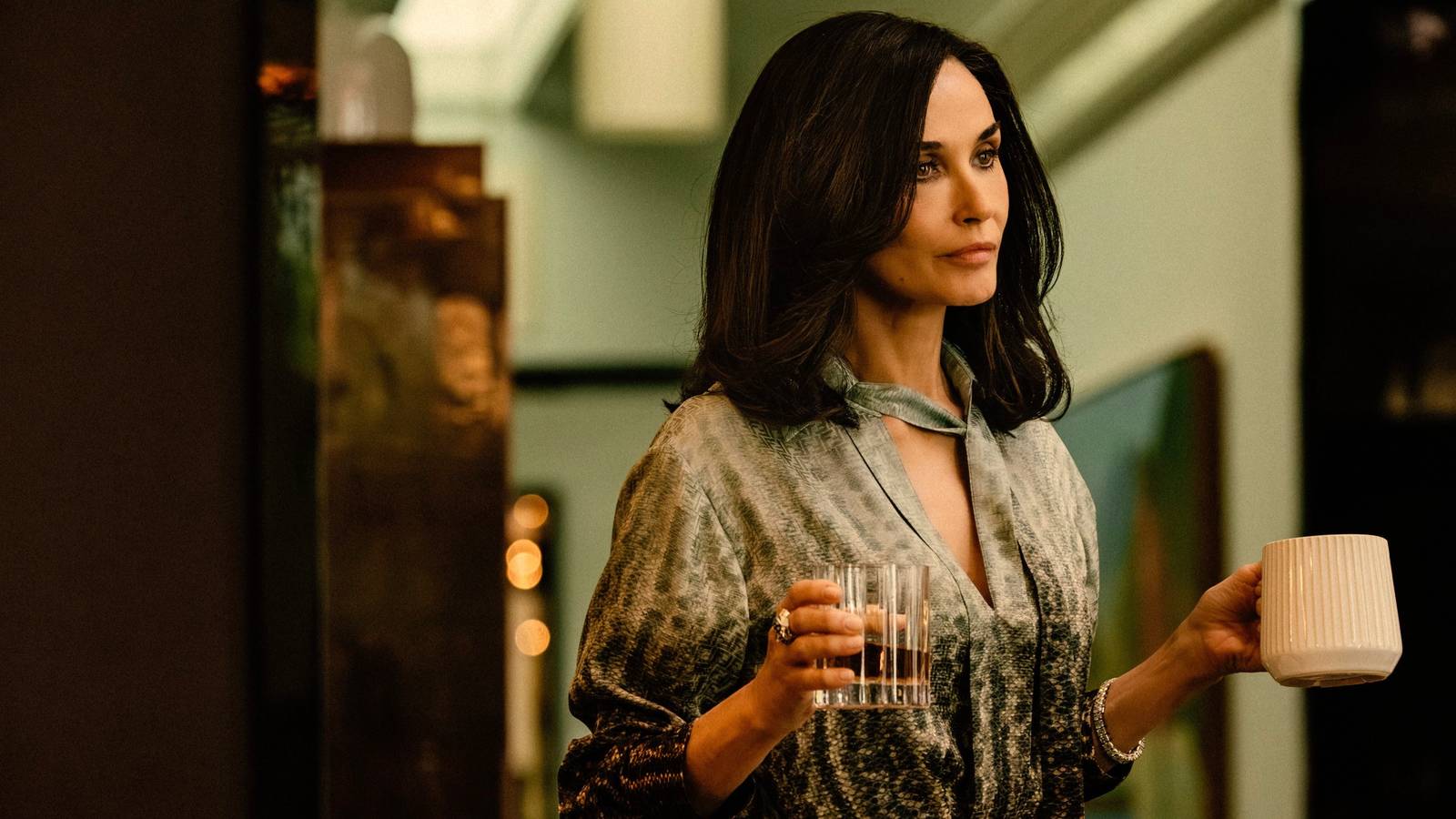 Cami Miller (Demi Moore) holding a glass of whiskey and mug of coffee in Landman season 1