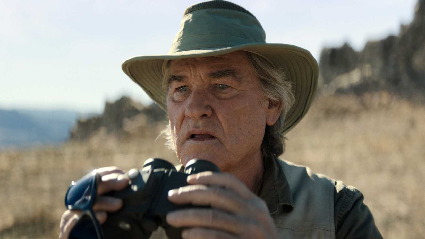 O mais velho Lee Shaw (Kurt Russell) observando com binóculos em Monarch: Legado de Monstros.